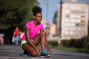 Mujer afroamericana runner apretando los cordones de los zapatos foto