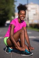 Mujer afroamericana runner apretando los cordones de los zapatos foto