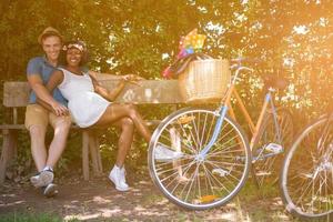 joven pareja multiétnica dando un paseo en bicicleta en la naturaleza foto