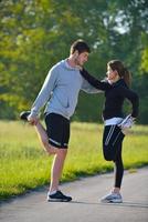 pareja haciendo ejercicio de estiramiento después de trotar foto