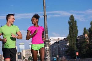 joven pareja multiétnica sonriente trotando en la ciudad foto