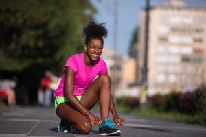 Mujer afroamericana runner apretando los cordones de los zapatos foto