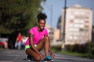 Mujer afroamericana runner apretando los cordones de los zapatos foto