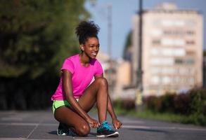 Mujer afroamericana runner apretando los cordones de los zapatos foto