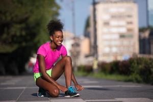 Mujer afroamericana runner apretando los cordones de los zapatos foto