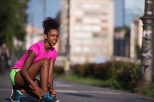 Mujer afroamericana runner apretando los cordones de los zapatos foto