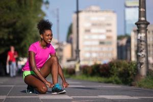 Mujer afroamericana runner apretando los cordones de los zapatos foto