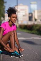 Mujer afroamericana runner apretando los cordones de los zapatos foto