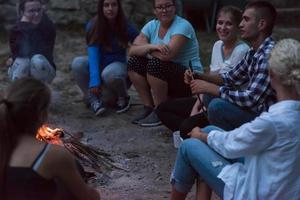 young friends relaxing around campfire photo