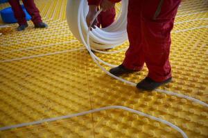 workers installing underfloor heating system photo