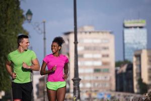 joven pareja multiétnica sonriente trotando en la ciudad foto