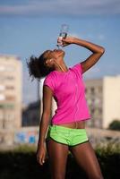 african american woman drinking water after jogging photo