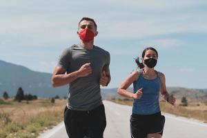 Young man and woman in protective masks running and doing exercises outdoors in the morning. Sport, Active life Jogging during quarantine. Covid-19 new normal. Selective focus. photo