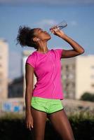 african american woman drinking water after jogging photo