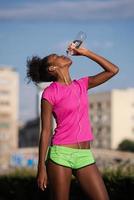 african american woman drinking water after jogging photo