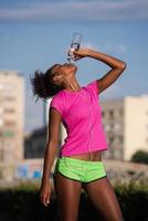 mujer afroamericana bebiendo agua después de trotar foto