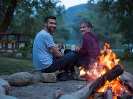 couple sitting around the campfire at evening photo