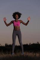 mujer negra está haciendo ejercicio de estiramiento relajándose y calentándose foto