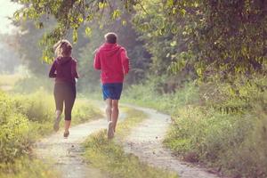 young couple jogging along a country road photo