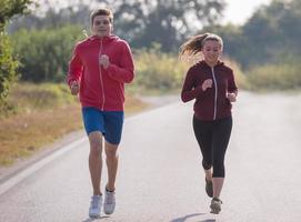 young couple jogging along a country road photo