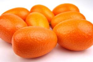 A group of fresh kumquats lies on a white surface. photo