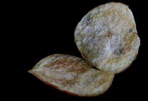 Crispy potato chips are isolated on a black background. photo