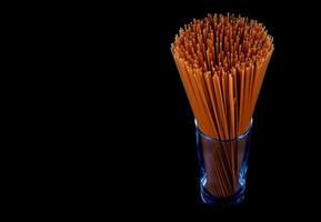 Long pasta isolated on black background. Red tomato pasta. Italian pasta in a glass glass. photo