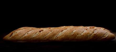 baguette crujiente fresca sobre un fondo oscuro. foto