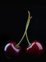 Two ripe cherry berries on a black background. photo