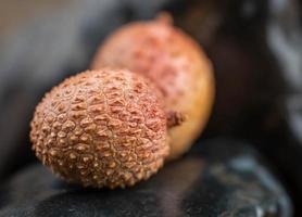 Lychees lie on dark stones. Selective focus. photo