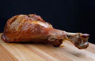 Baked turkey shin on a wooden cutting board. photo