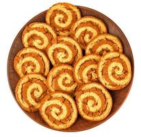 A beautiful cookie with a spiral pattern on a clay plate is isolated on a white background. photo