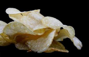 Delicious crispy potato chips on a black background. photo