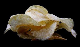 Delicious crispy potato chips are isolated on a black background. photo