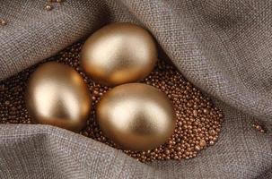 Three golden eggs on gold sand. photo