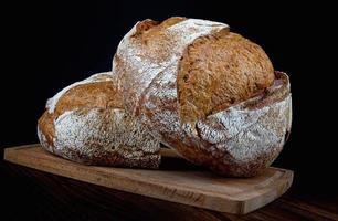 Two loaves of rustic bread on a wooden board. Homebaked bread . photo