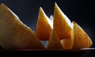 The slices of ripe melon shining on the light lie on a plate. photo