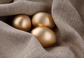 tres huevos dorados sobre un fondo de tejido. foto