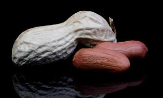 Peanuts in the shell and without it on a black background. photo