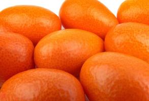 A group of fresh kumquats lies on a white surface. photo