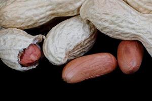 Peanuts in the shell and without it on a black background. photo