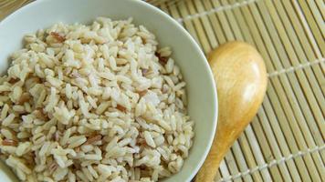 BROWN RICE in white bowl on wood table for health food content. photo