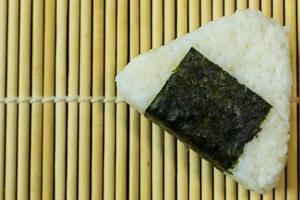 la comida japonesa onigiri arroz blanco formado en formas triangulares o cilíndricas y, a menudo, envuelto en nori. foto