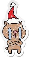 crying pig distressed sticker cartoon of a wearing santa hat vector