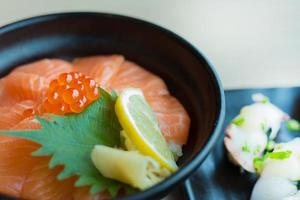 A salmon ikura don in black bowl image close up in japanese restaurant . photo