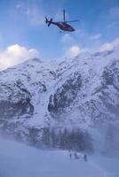 rescue team with a red helicopter rescuing a hurt skier photo