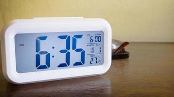 The white alarm clock digital numbers on wood table. photo