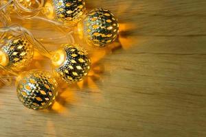 decoración de bolas de luces doradas de navidad en mesa de madera. foto