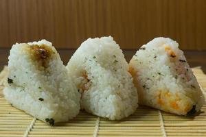 la comida japonesa onigiri arroz blanco formado en formas triangulares o cilíndricas y, a menudo, envuelto en nori. foto