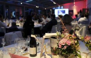 evento nocturno con flores y botellas de vino en las mesas foto